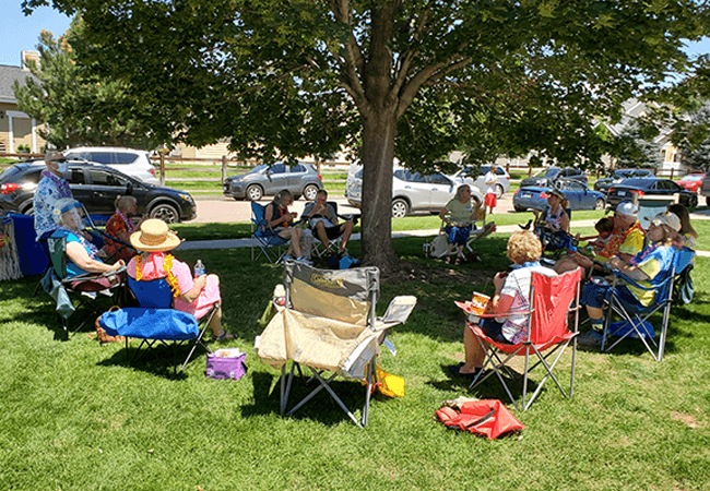 A group of senior citizens gathered around a tree for a picnic